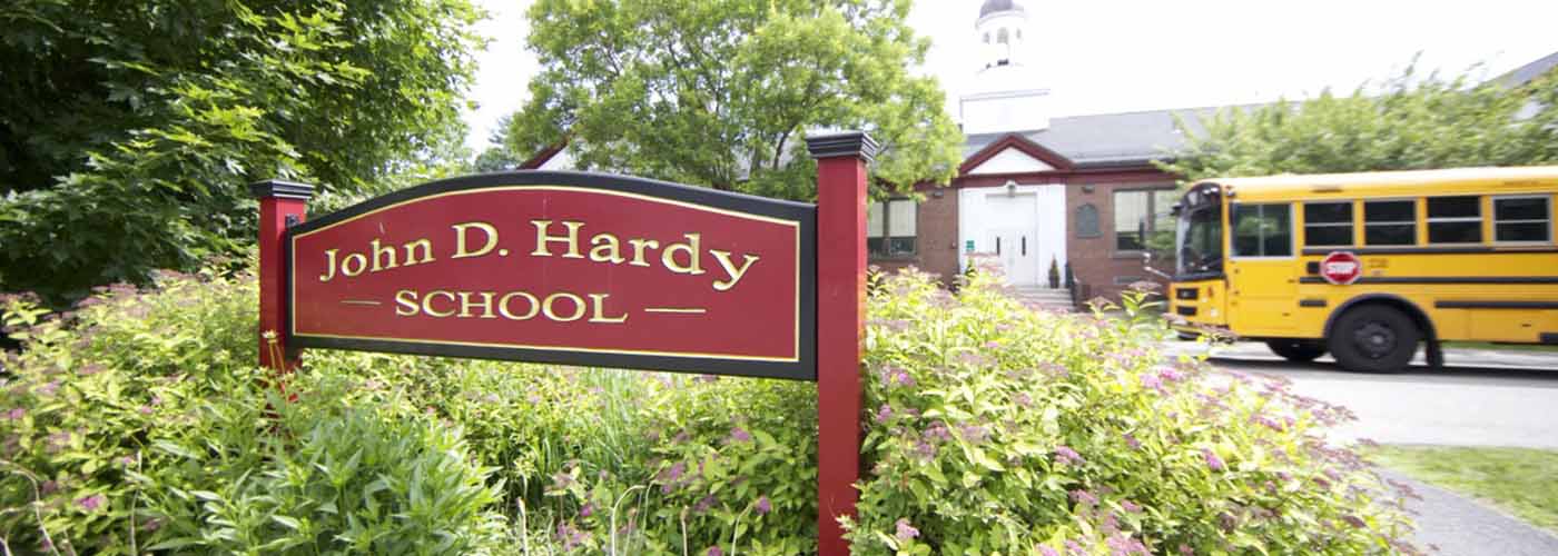 Hardy School exterior with sign and school bus