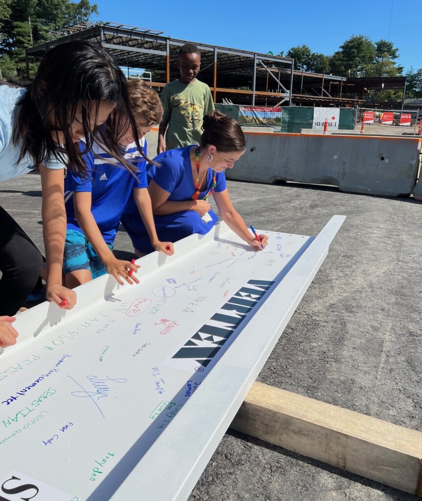 Fifth grade teacher and students sign the beam