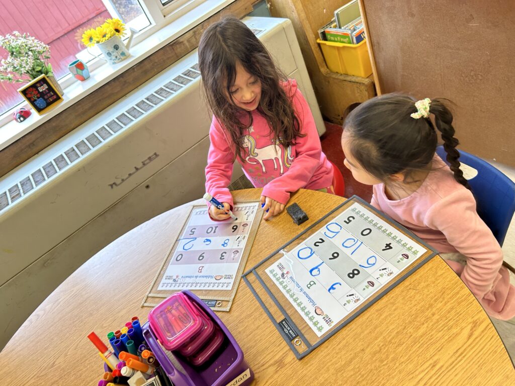 Two students sitting at a table working on a number chart