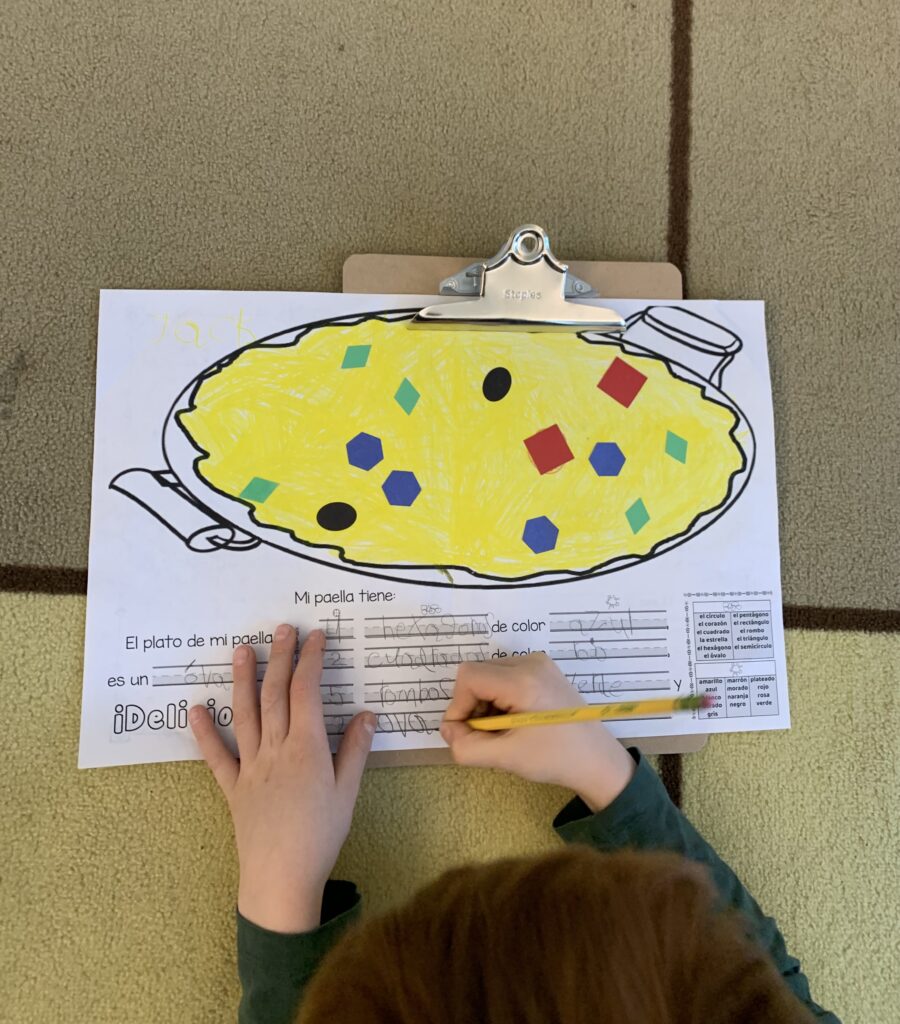 A view from above of a student's hands working on a worksheet titled Mi paella tiene (my paella has)