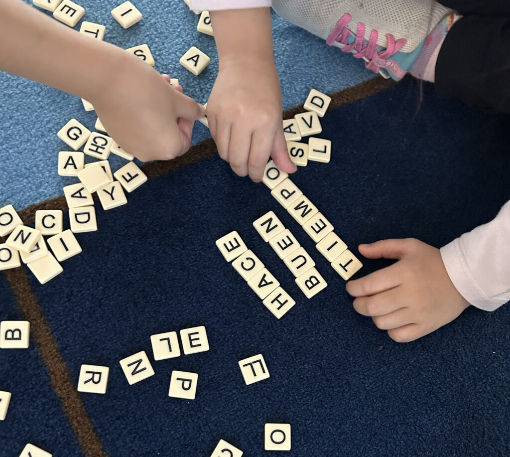 Students making words with white letter tiles on a blue background
