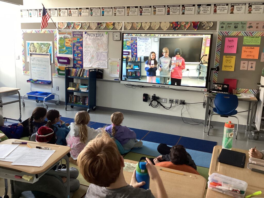 Students watching Spanish commercials they made on the classroom screen
