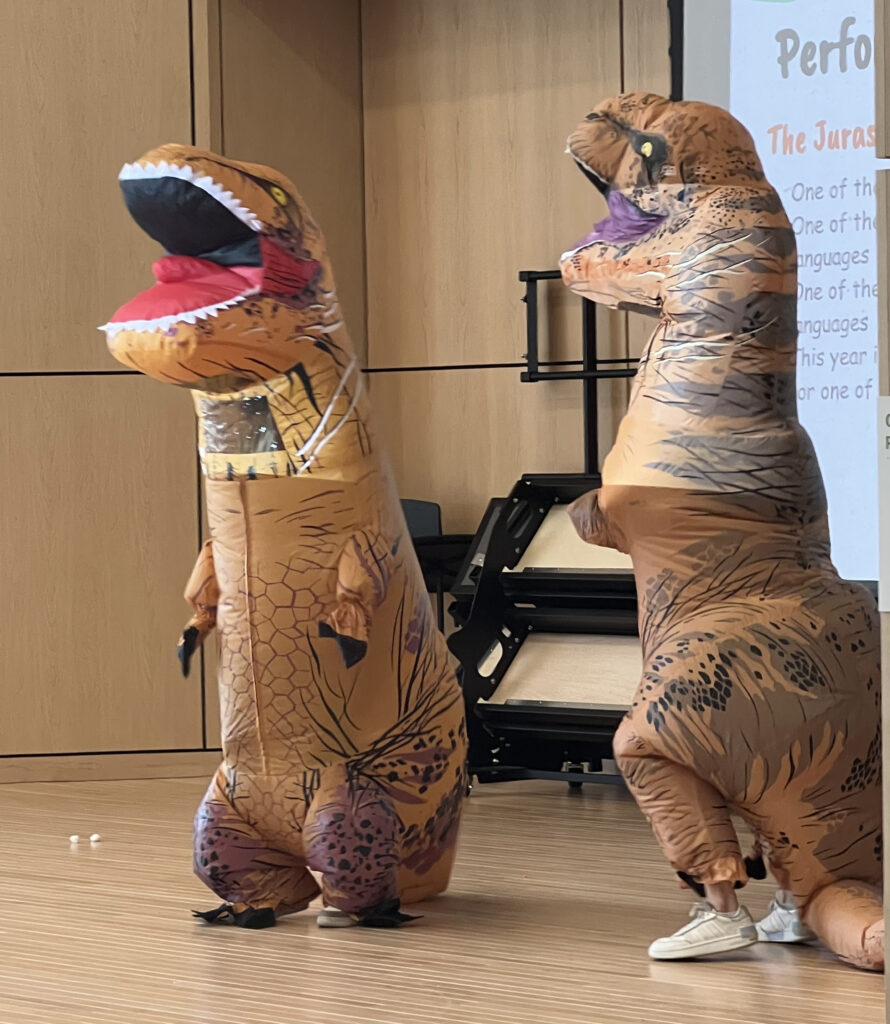 Two staff members wearing blow up Tyrannosaurus Rex costumes