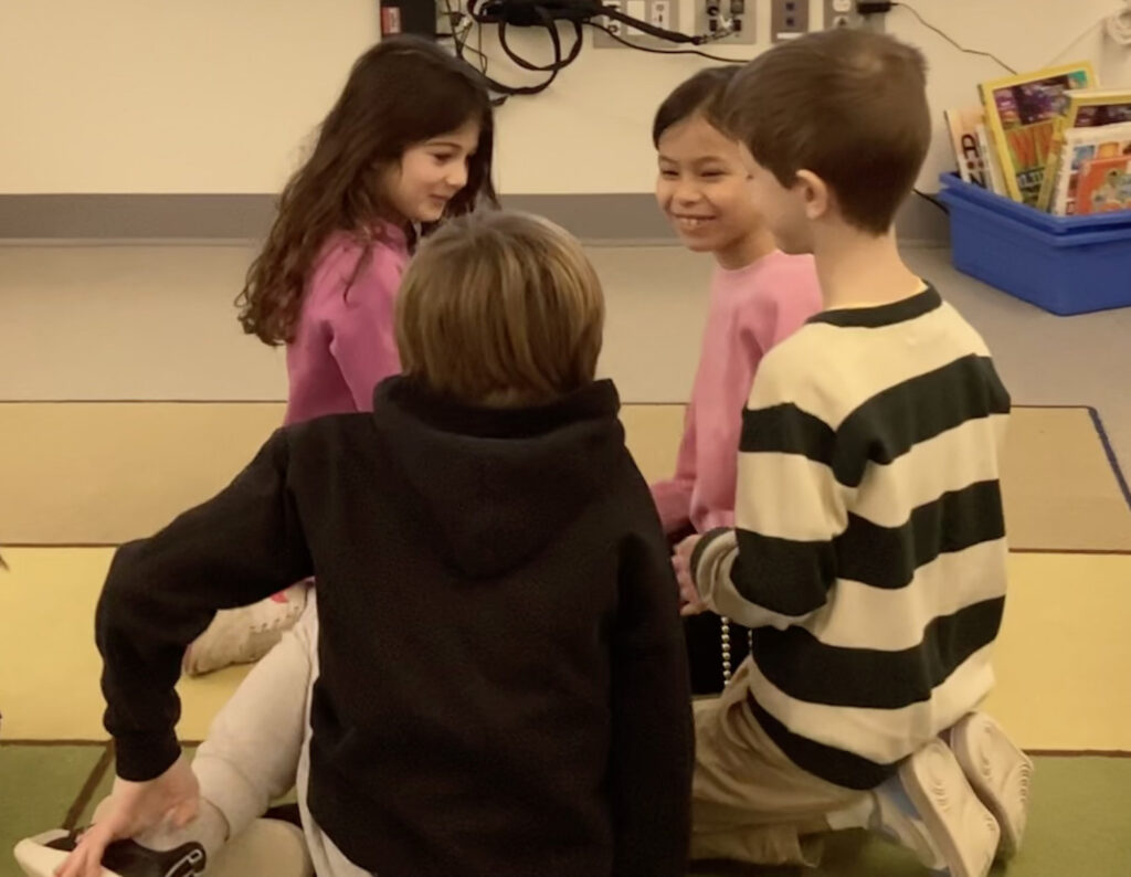 Four students sitting on the classroom floor communicating