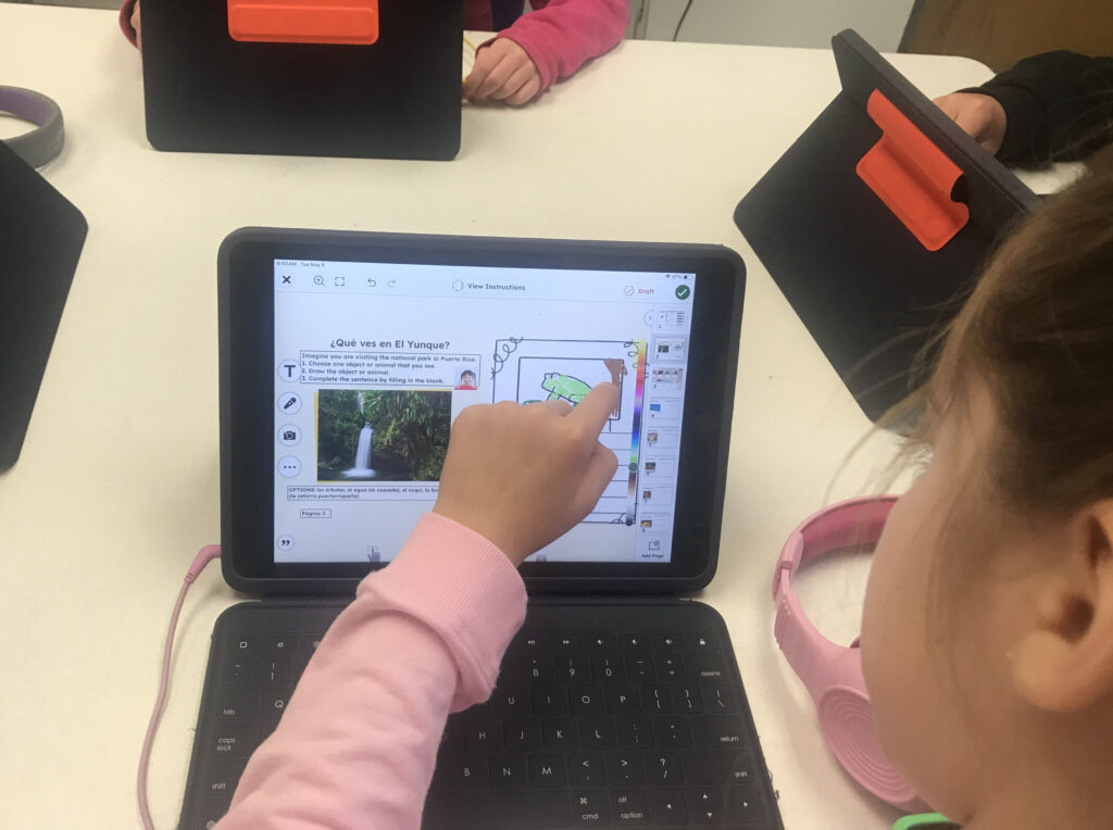 A student sitting at a classroom table using an iPad to learn about El Yunque National Park in Puerto Rico