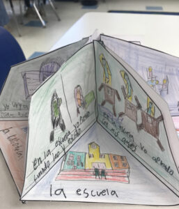 A pop-up storybook created by students open to a page about school (la escuela)