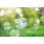 Iridescent bubbles floating over a grassy green background